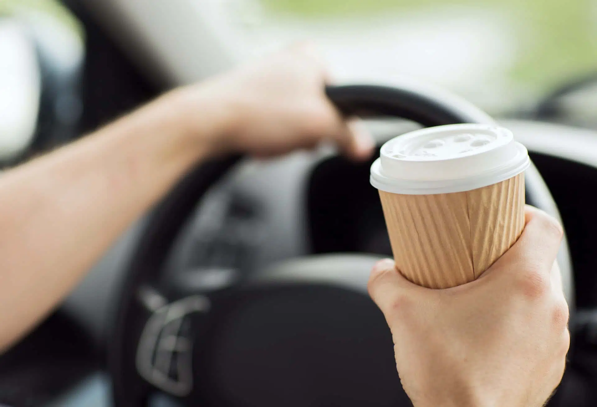Person driving whilst holding coffee cup
