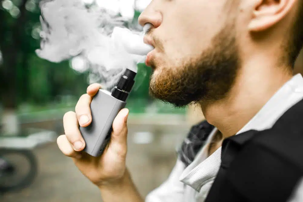Image of a non-descript man puffing on an e-cigarette