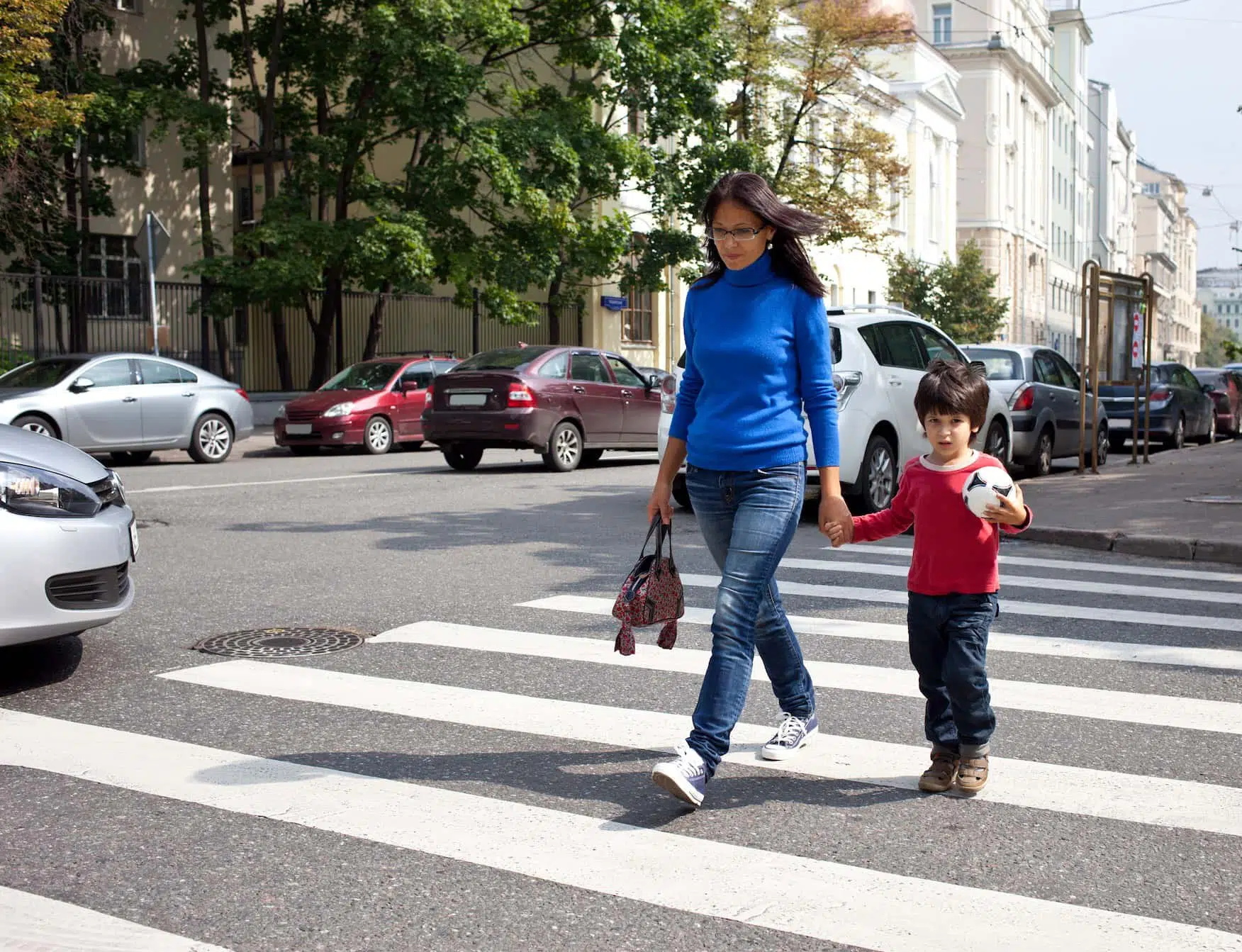 Image of a mother and her son walking across a pedestrian crossing.