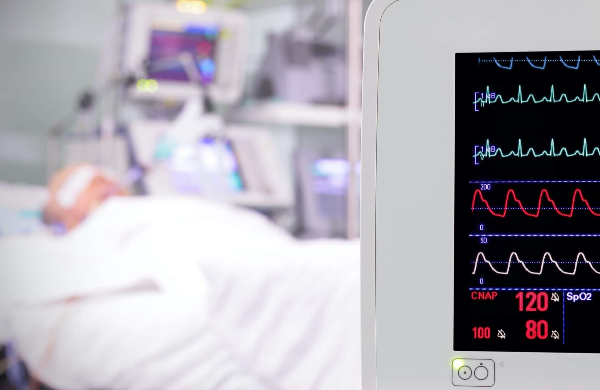 Close-up of medical equipment with patient in hospital bed in background