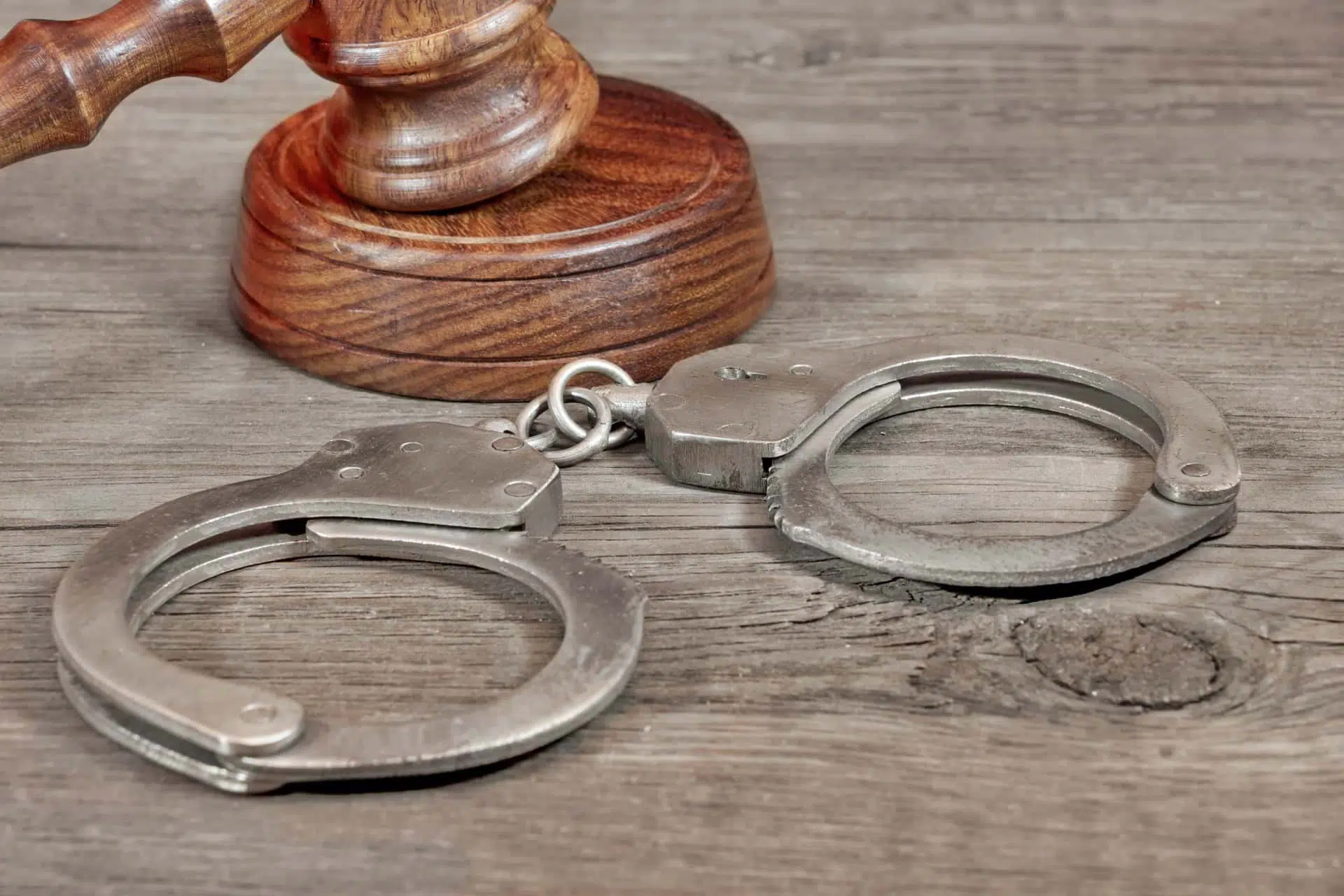 Pair of handcuffs on a desk next to a gavel