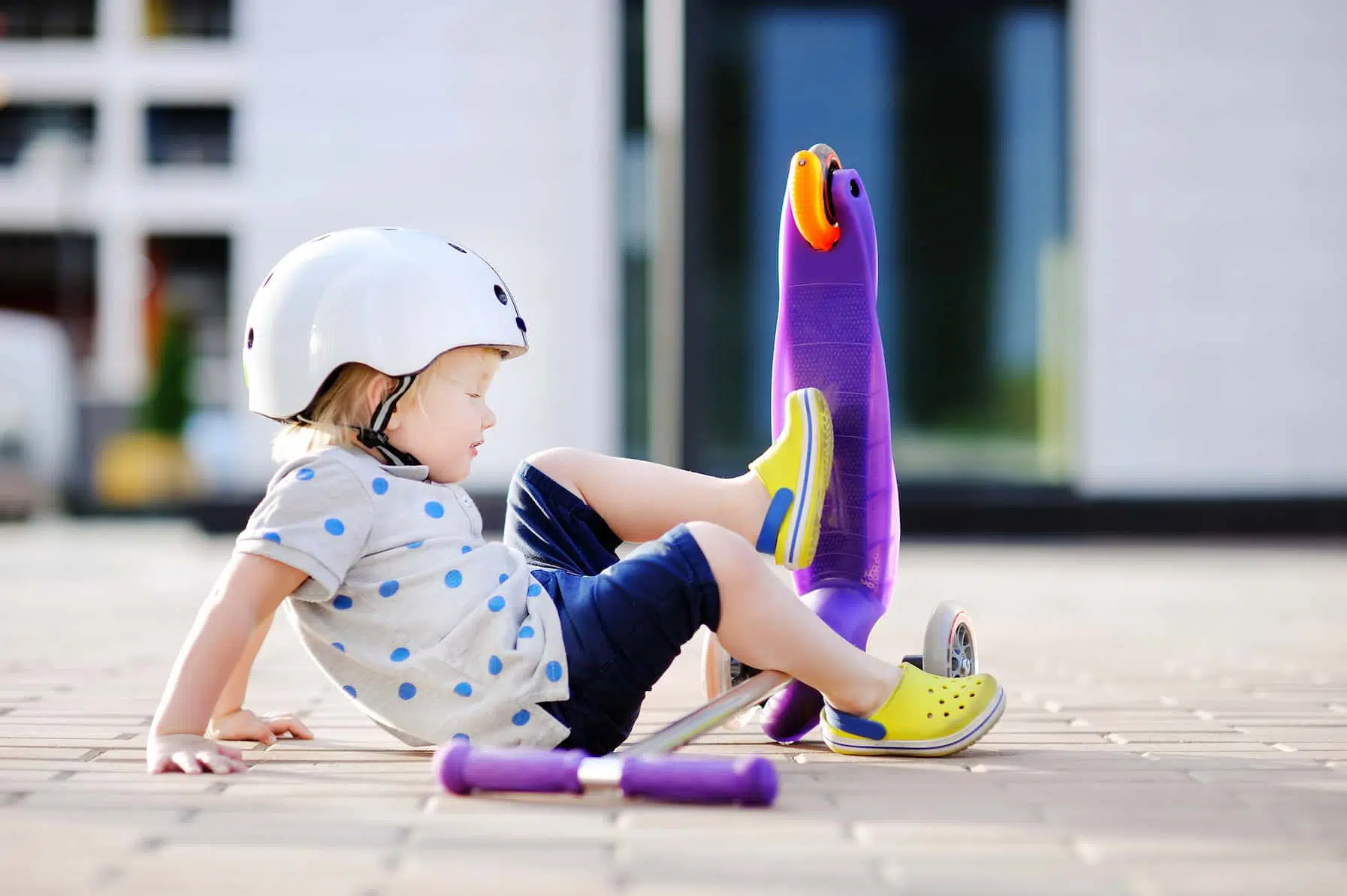 Image of a toddler girl who fell riding her scooter but was fortunately wearing a helmet and therefore engaging in Temecula youth injury prevention tactics.