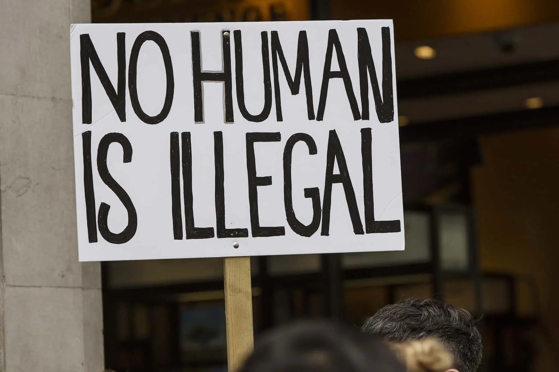 Image of a protest sign that reads "No human is illegal" in reference to California officially becoming a sanctuary state.