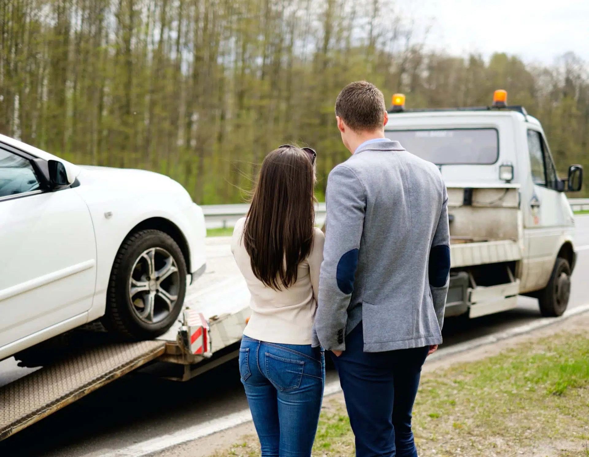 Couple watching their car be towed away after an auto accident